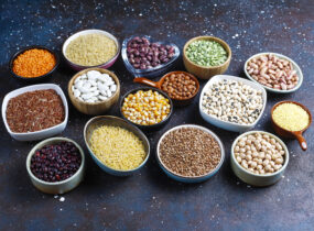 Legumes and beans assortment in different bowls on light stone b